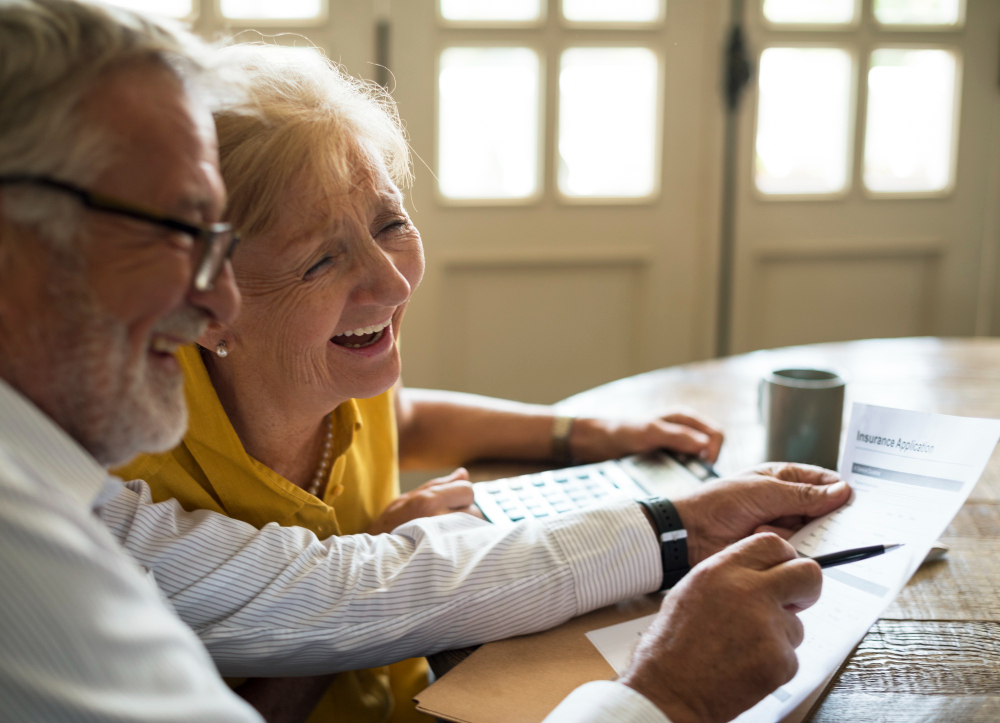 couple senior qui rigole en remplissant un formulaire